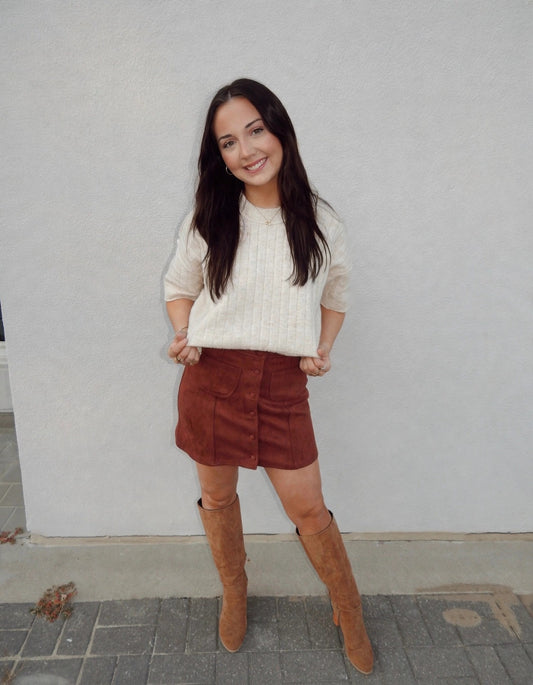 Ava wearing the Stretch Suede Button Front Mini Skirt in Burgundy with a cream sweater and tan boots